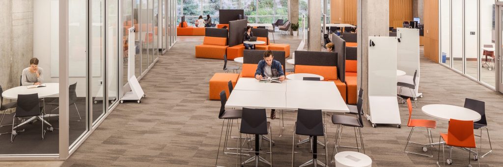The modern library, crafted by a California-based general contractor, features orange and black seating, white tables, and glass-walled study rooms. With large windows revealing lush greenery, patrons can enjoy reading or working on laptops in this Level 10 construction marvel.