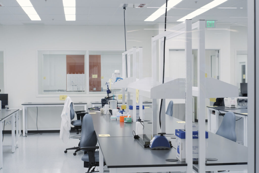 Clean laboratory with workbenches, equipment, and safety partitions.
