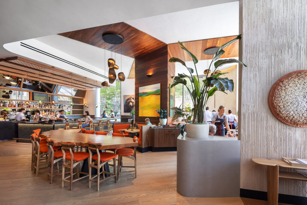 Poppy & Claro restaurant featuring a contemporary restaurant interior with custom wood detailing, high ceilings, pendant lighting, a full-service bar, and flexible dining areas.